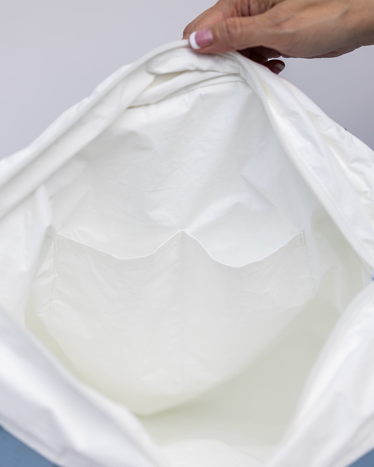 Close up inside Puakenikeni tyvek tote bag showing two open organizational pockets for keys, sunglasses and phones.