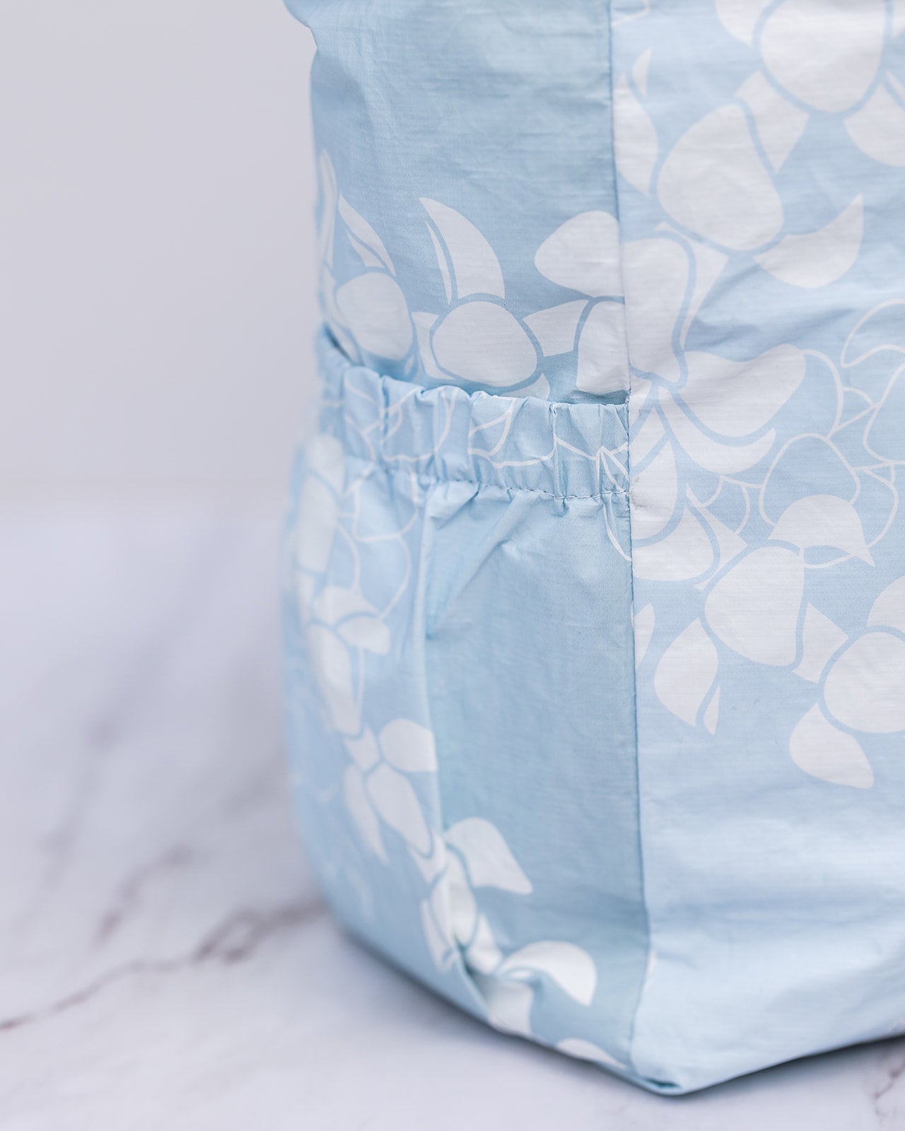 Close_up_of_Puakenikeni_lei_tyvek_tote_cinched_water_bottle_side_pockets