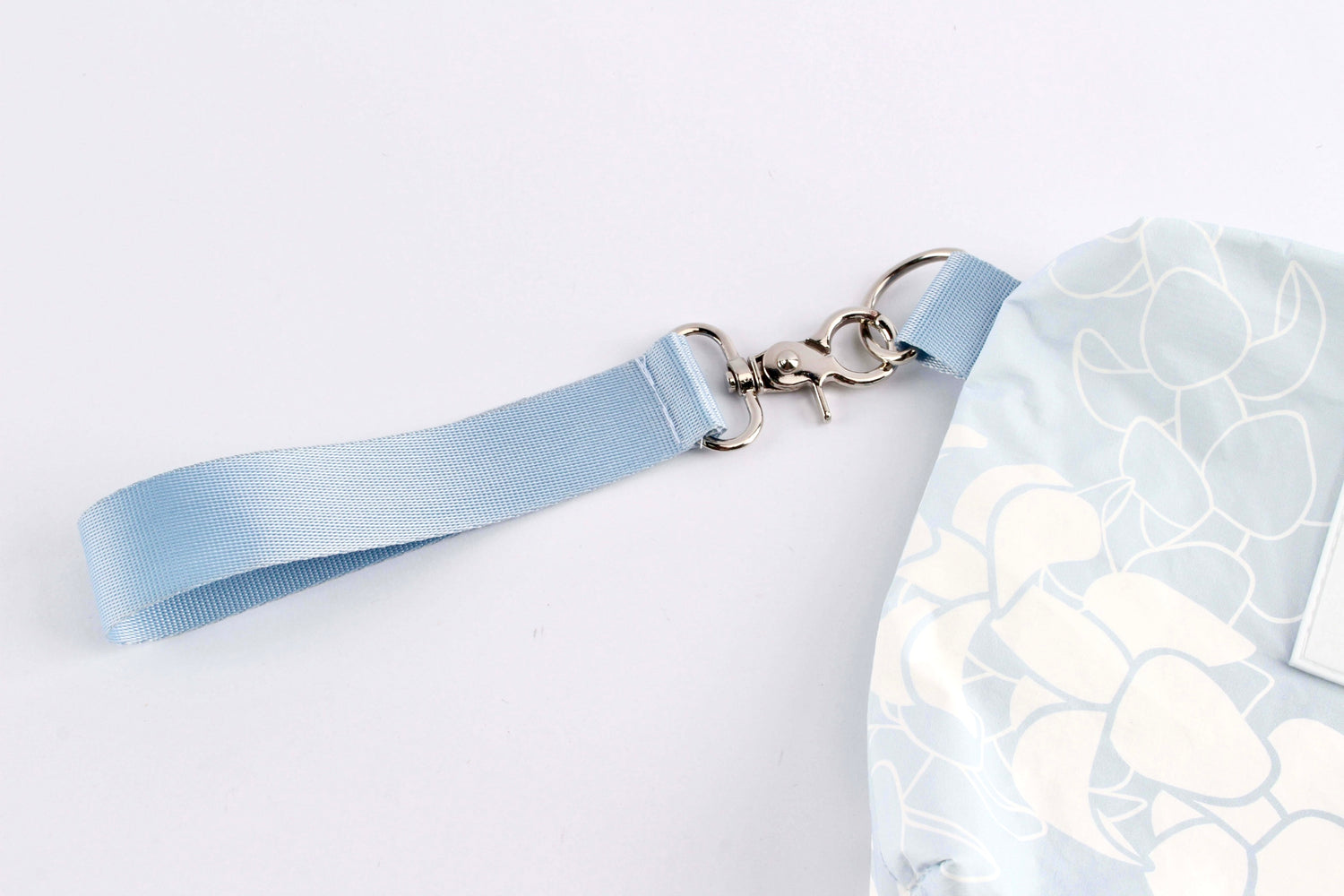 Close up of Puakenikeni wristlet accessory pouch showing metal side ring and detachable wristlet strap.