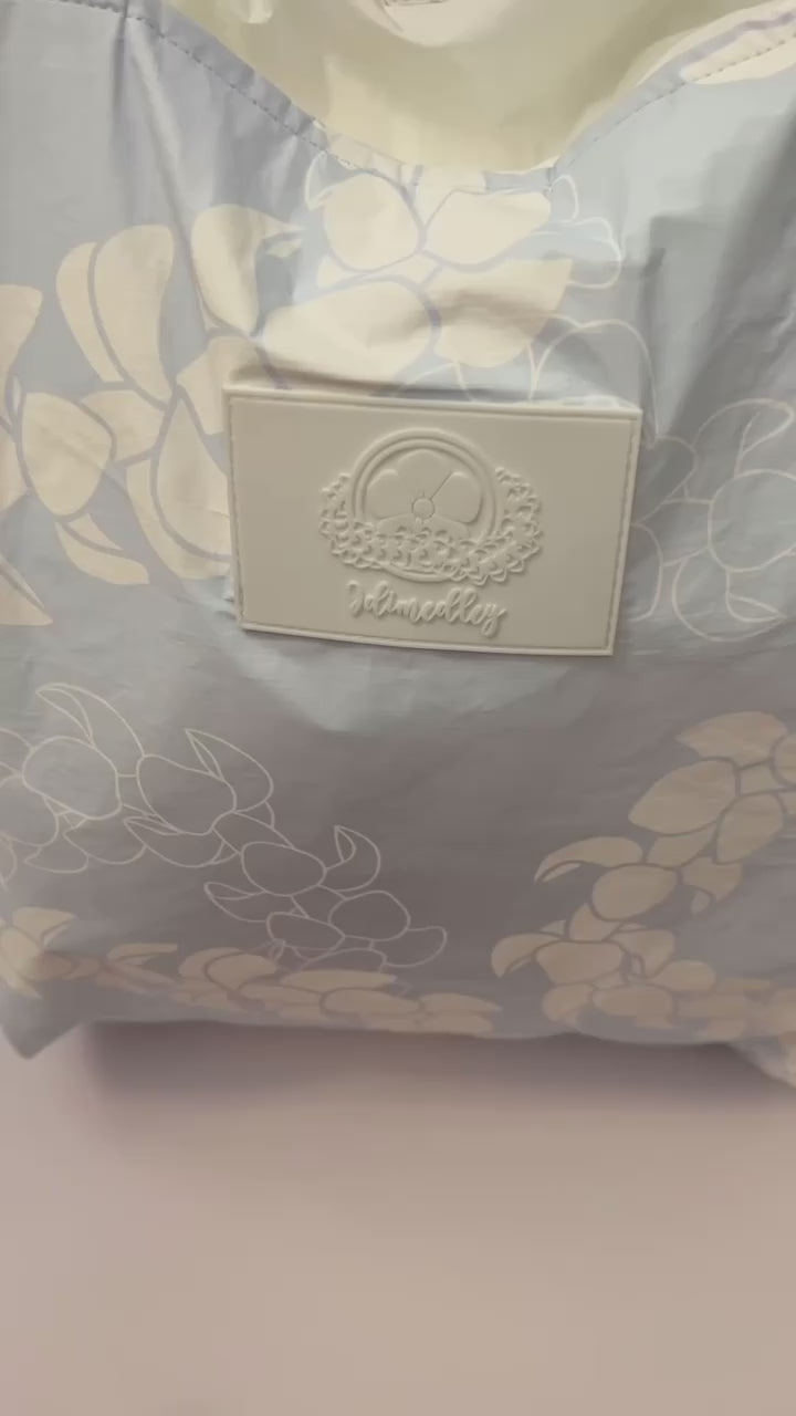 Light blue puakenikeni tyvek tote bag video showcasing 7 pockets and luggage trolley sleeve.