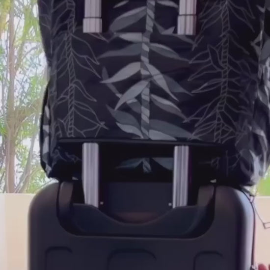 Video showcasing black ti leaf expandable, waterproof tote’s luggage trolley sleeve and 7 organizational pockets.  2 water bottle side pockets, luggage trolley zips up, outside and inside zippered pockets and two inside organizational pockets for phone, sunglasses and keys. 