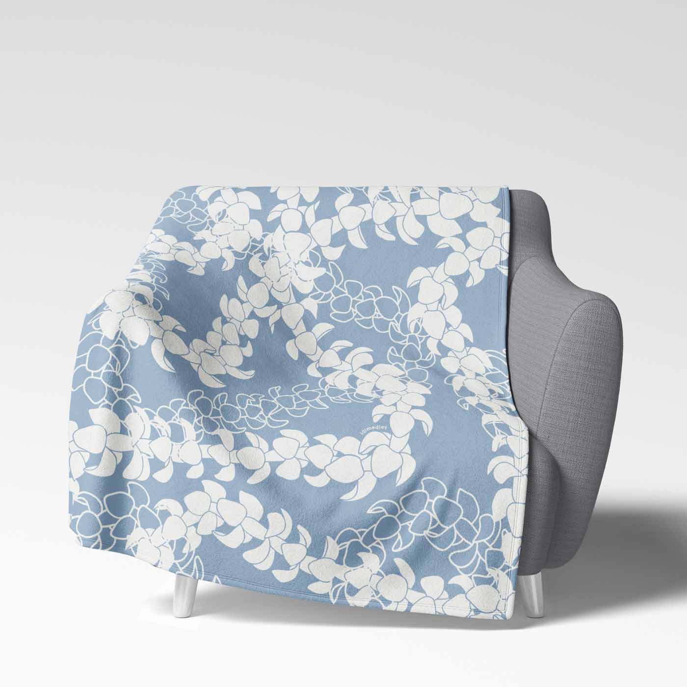Soft velveteen blanket with a design displaying multiple Puakenikeni flower lei strands in white silhouettes and line art on a light blue background.