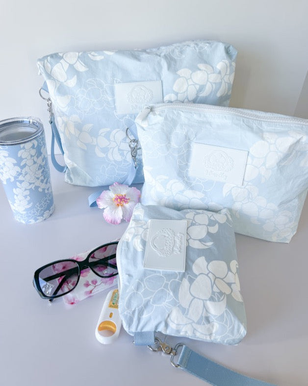Puakenikeni lei zippered tyvek wristlet pouches showing sunglasses, tissue and cup for size reference.