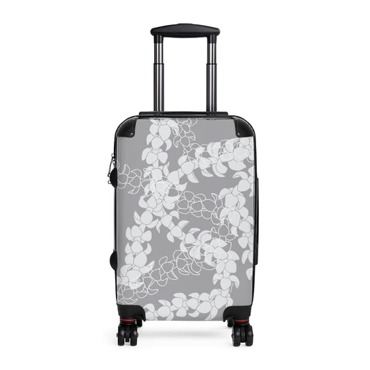 Rolling, hard shell carryon luggage with gray and white Puakenikeni flower lei design. 