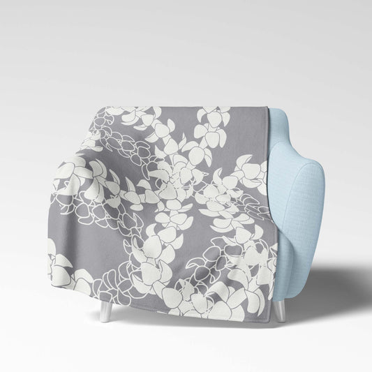 Soft velveteen blanket with a design displaying multiple Puakenikeni flower lei strands in white silhouettes and line art on a gray background.